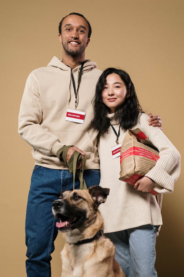 Smiling volunteers with a dog and donation bags in a studio setting.